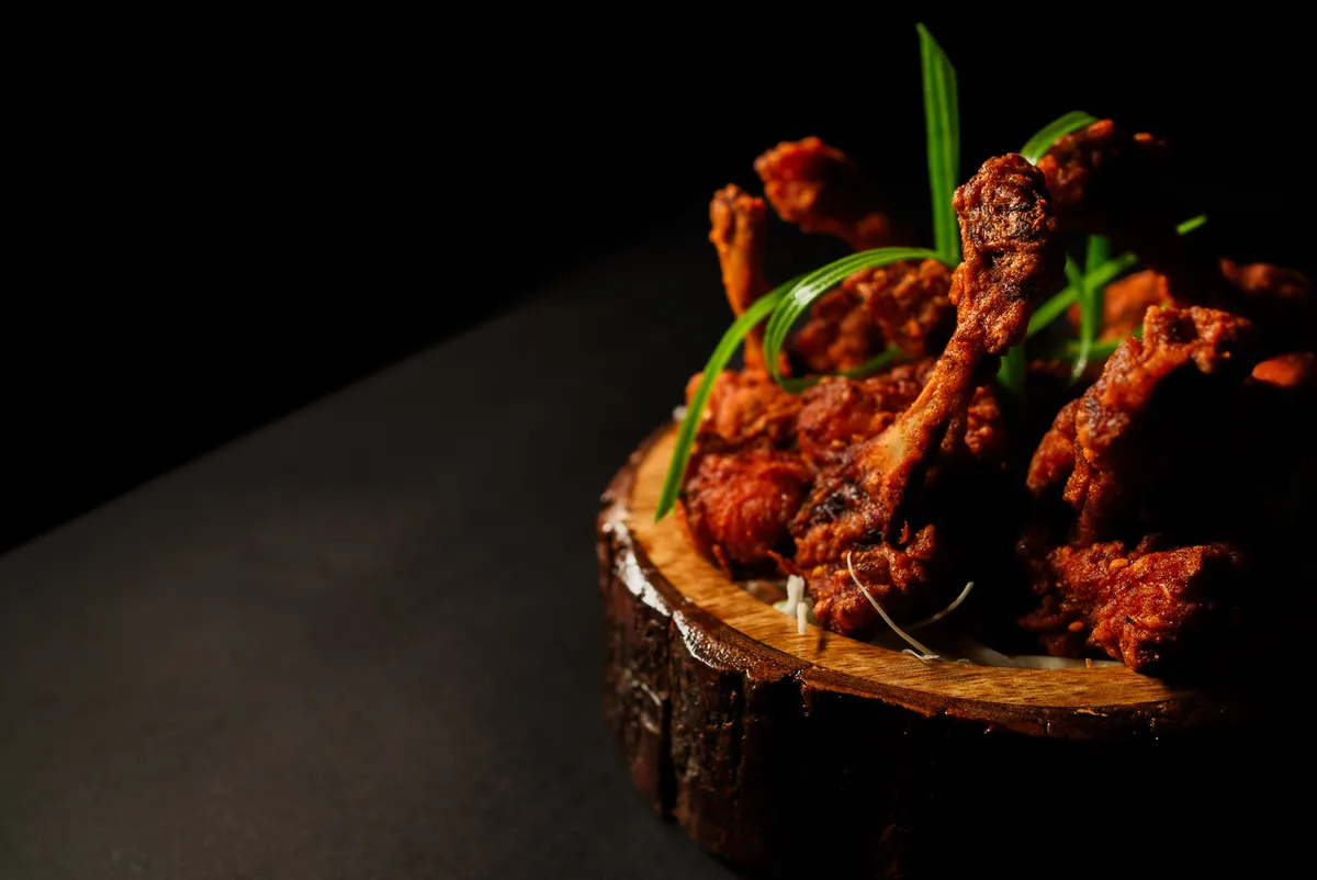 Delicious Indian-style fried chicken drumsticks on a rustic wooden platter, perfect for food lovers.